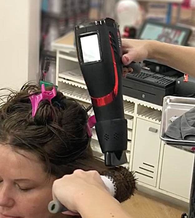Hairdresser using SnozzlePro adapter on a black hair dryer with a concentrator nozzle