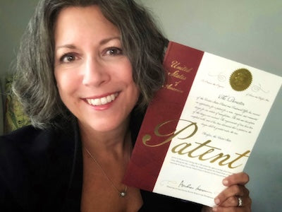SnozzlePro inventor holding a United States patent certificate and smiling