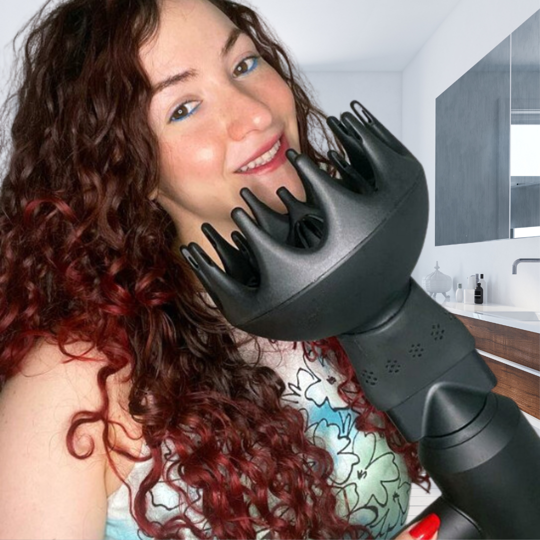 Woman with curly red and brown hair using a black hair dryer with a diffuser attachment and a SnozzlePro universal hair dryer attachment nozzle adapter in a modern bathroom.