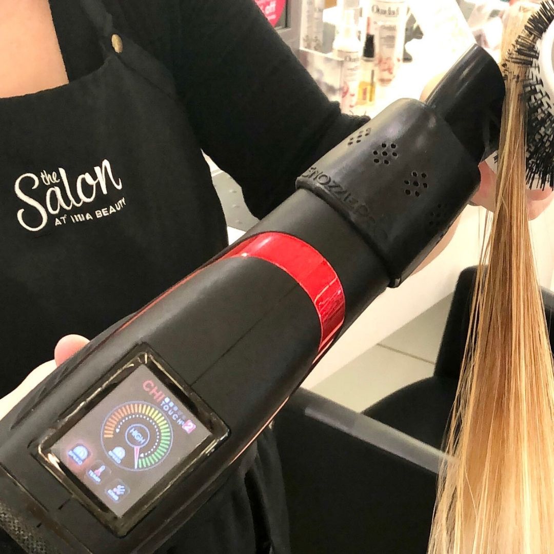Hairdresser using a SnozzlePro concentrator nozzle on their hair dryer while blowing out a client's hair